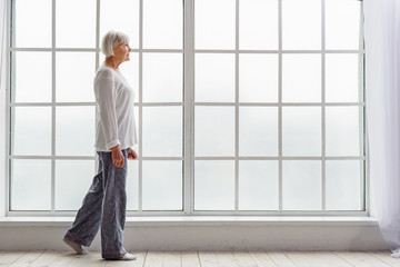 Outgoing old woman moving in room of clinic