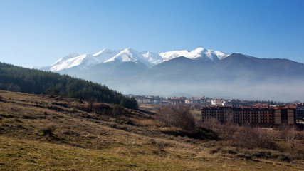 Fototapeta premium Snow peaks over the Bansko town, Razlog, Bulgaria