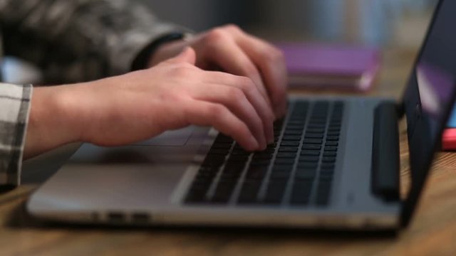 Closeup of man's hands working on laptop