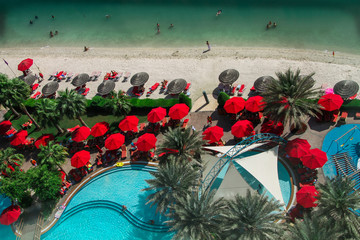 Obraz na płótnie Canvas Bird's eye view of swimming pool in luxury hotel with red stylish umbrellas
