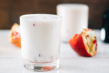 Traditional indian lassi - cold yougurt drink on white table with pomegranate seeds