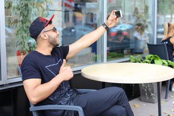 Young guy arab male man makes selfie, talks on Skype, smiles and