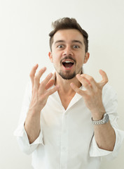 Portrait of young angry man. Angry shouting man at somebody. Screaming man gesturing with hands on white background.