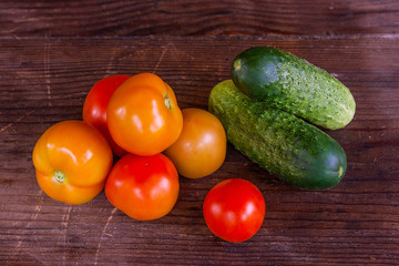 Close up view of fresh, ripe tomatoes and cucumbers on wood back