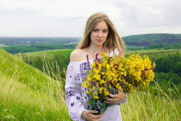 Outdoor portrait of beautiful blonde woman, attractive young girl in camomile field with flowers. Young beautiful girl in the field in summertime. Cosmos flowers in hands. Girl with bouquet of flowers