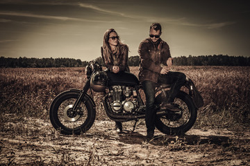 Plakat Young, stylish cafe racer couple on vintage custom motorcycles in field