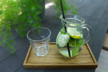 Glass decanter and glass faceted cup stands on plank on table in