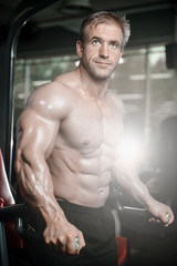 Obraz premium Brutal strong bodybuilder man pumping up muscles and train gym