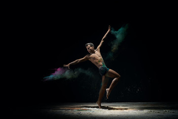 Naked man dancing on stage in cloud of color dust