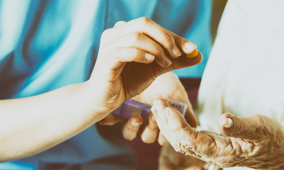 Hand of young nurse giving medical pill to elderly woman - Powered by Adobe