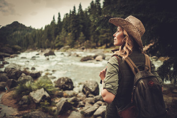 Beautiful woman hiker near wild mountain river - obrazy, fototapety, plakaty