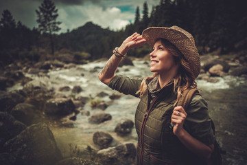 Beautiful woman hiker near wild mountain river