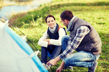 happy couple setting up tent outdoors