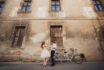 The happinest couple in love stands near bicycle