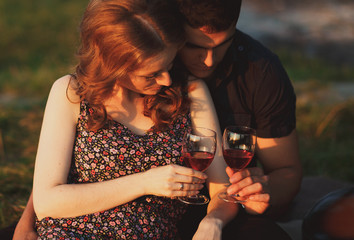 The charming couple in love with glass of champagne  sit on the