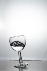 Transparent glass cup with a pouring bubbling cold fresh water with bubbles and drops