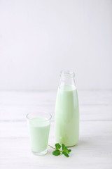 Milk cocktail with mint on a rustic white table
