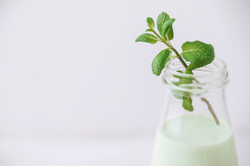 Milk cocktail with mint on a rustic white table