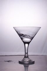 Transparent glass cup with a pouring bubbling cold fresh water with bubbles and drops