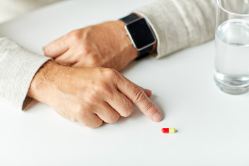 close up of senior man with water, pill and watch