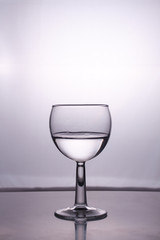 Transparent glass cup with a pouring bubbling cold fresh water with bubbles and drops
