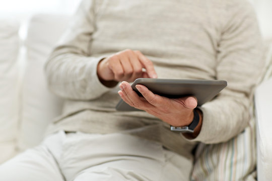 close up of senior man with tablet pc at home