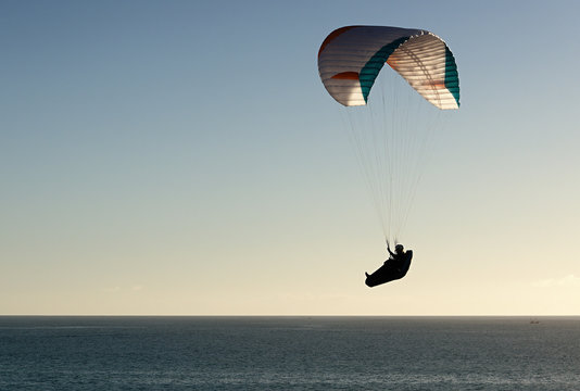 Paraglider flying at sunset over the ocean