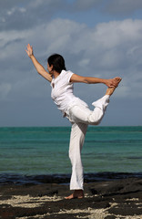 Eine Frau macht Yoga am Strand von Mauritius