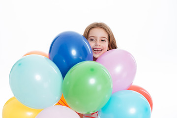 Fototapeta na wymiar Cheerful little girl holding colorful balloons and having fun