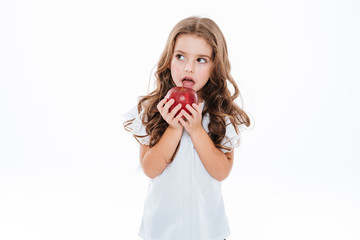 Pensive worried little girl standing and holding red apple
