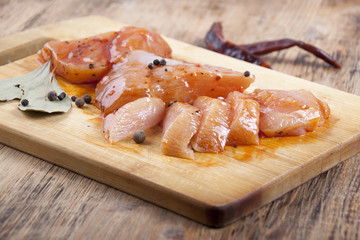 Raw chicken fillets in the marinade on a cutting board