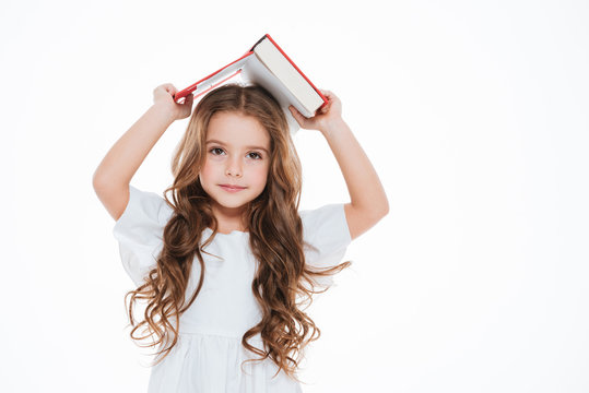 Pretty little girl standing and holding book above her head