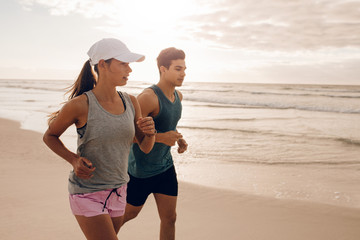Fitness couple running at beach