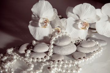 Fototapeta na wymiar white orchids and pearls lie on the rocks 