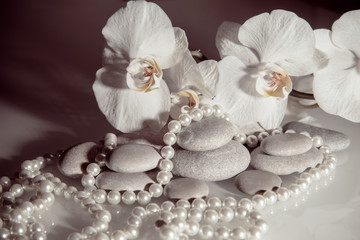 white orchids and pearls lie on the rocks 