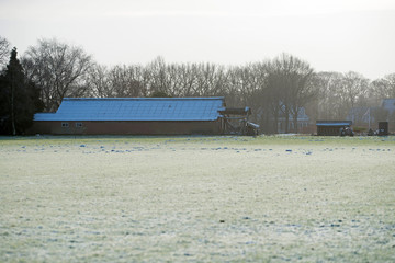 Farm cattle shed with frozen roof in rural winter landscape.