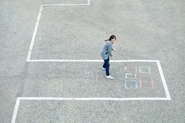 Cheerful girl draws chalk house / building