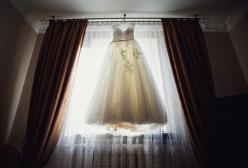 The wedding dress hangs on the hanger