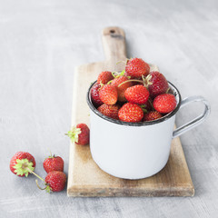 Fresh strawberry in a metallic cup on wooden desk.