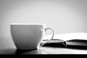 Cup of coffee and book on wooden table