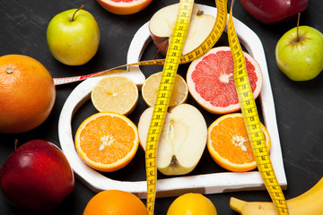 Diet, fruits and centimeter on a black background
