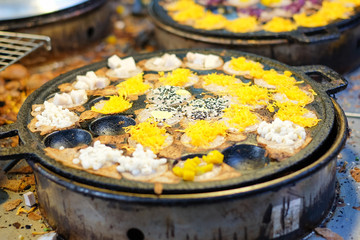 "Khanom Krok" or grilled rice flour pancake with sesame, coconut and other in black hole stove , Thailand dessert.