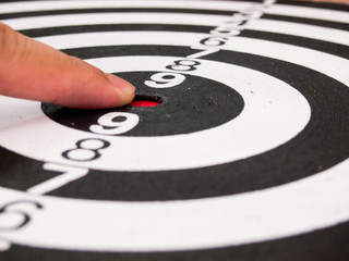 Black and white dart with hand point at center (Concept for targ