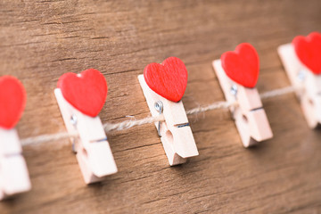 Valentines day concept background.The red heart shape clothespins hanging on rope with retro wood floor background.