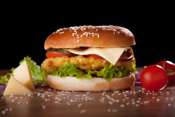 Burger with chicken and cheese, lettuce, cucumbers, tomatoes and onions.