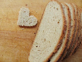 Foto auf Leinwand Heart shaped piece of bread in front of full bread © melih2810