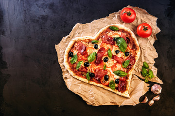 Heart shaped pizza with tomatoes and mozzarella for Valentines Day on vintage black background....