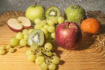 Fresh fruits, apples, kiwi, grapes and mandarin with drops of water