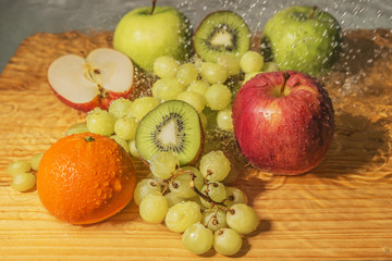 Fresh fruits, apples, kiwi, grapes and mandarin with drops of water