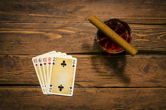 Playing cards, cigar and drink on the old boards